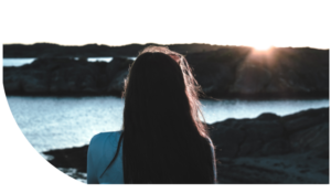 Awareness - Young woman thinking by sea during sunrise.