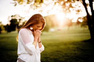 A woman in prayer outside.