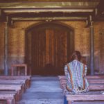 Seeking the pleasure of the Lord. Woman praying sitting on wooden bench pew.