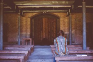Seeking the pleasure of the Lord. Woman praying sitting on wooden bench pew.
