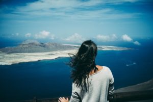 young woman watching ocean view and island in horizon, thinking